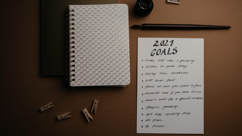 Aesthetic flatlay of notebooks and a 2021 goals list in elegant calligraphy.